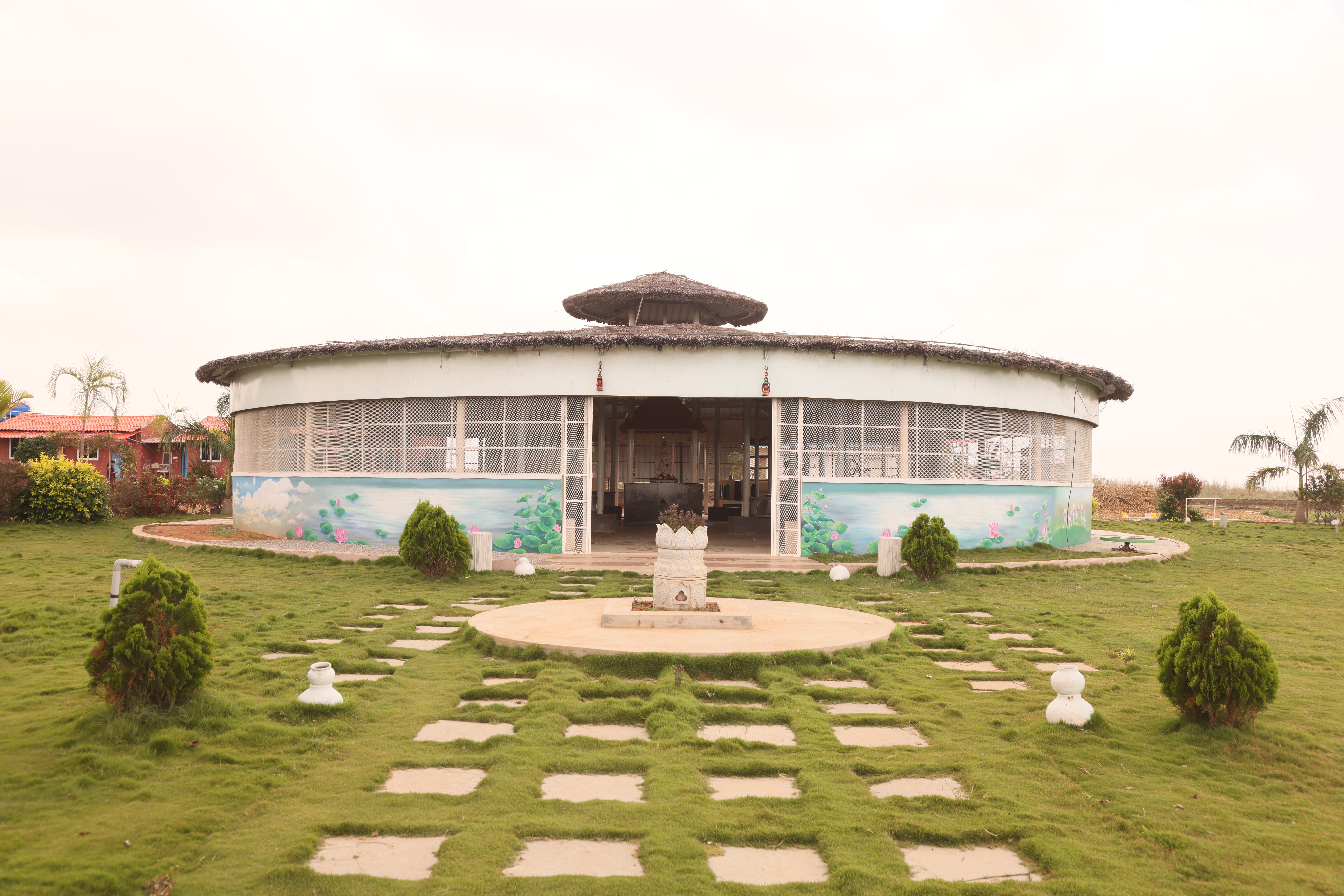 A circular community building at Farm Natura with a lush green lawn.